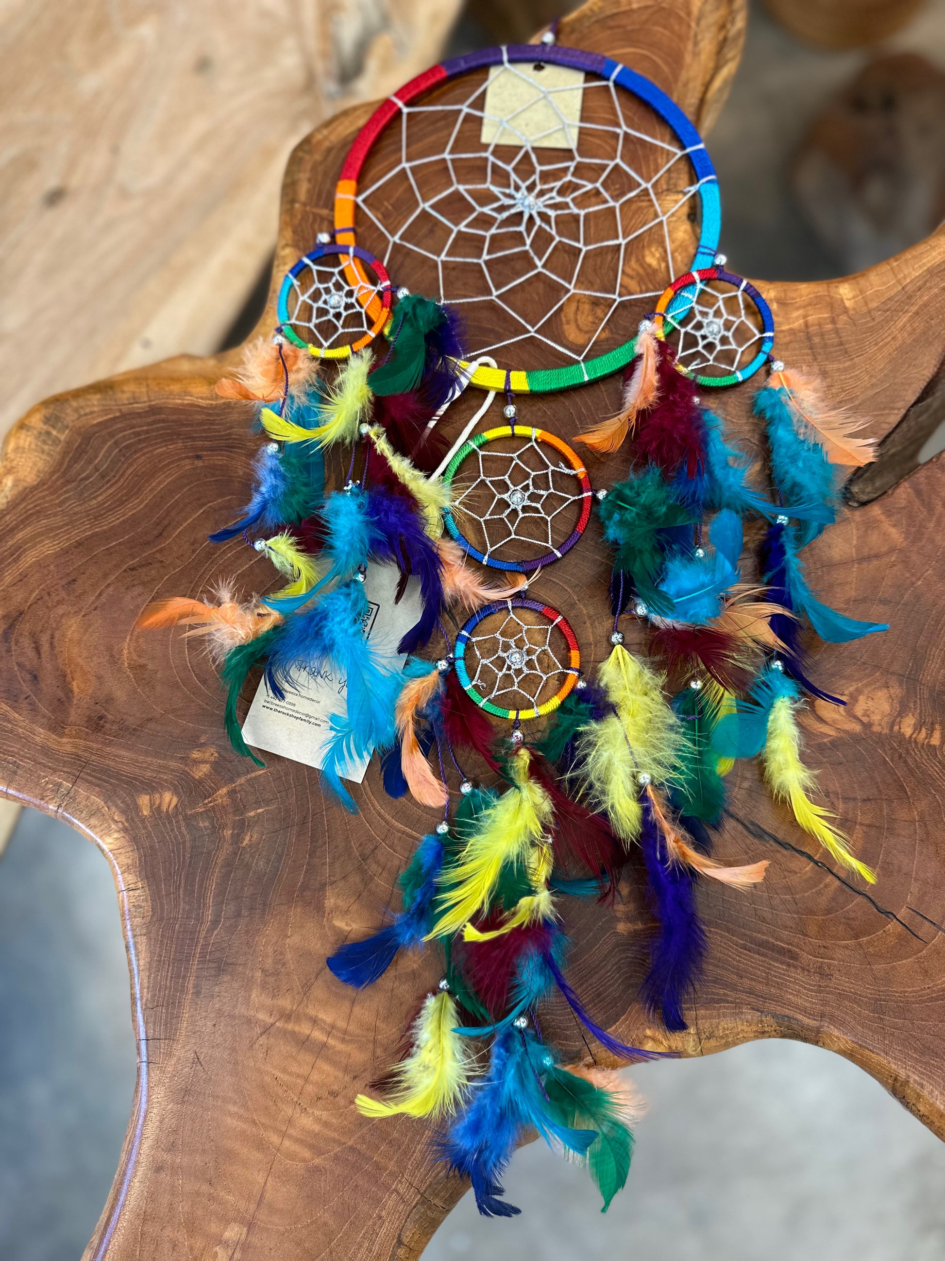 vibrant rainbow dreamcatcher with colorful feathers resting on a rustic wooden table