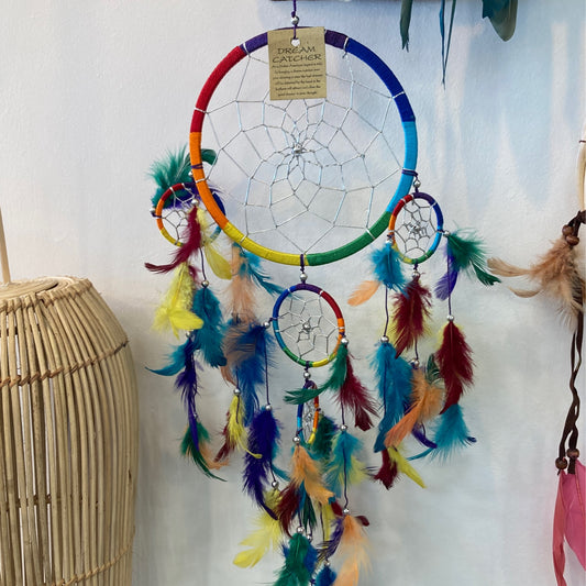 vibrant rainbow dreamcatcher with colorful feathers resting on a rustic wooden table