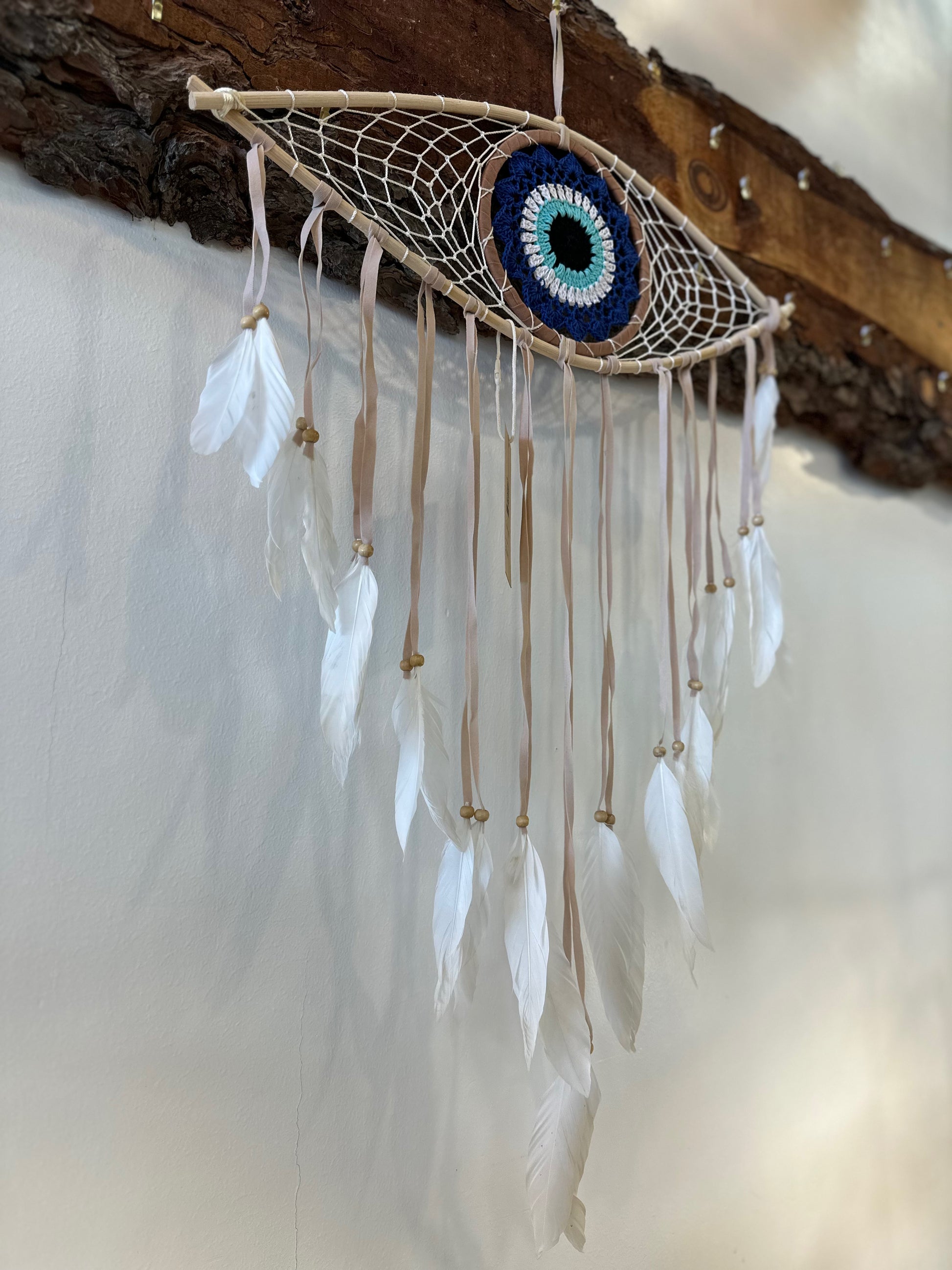 large dreamcatcher shaped like an eye with a blue iris and white feathers hanging from the bottom