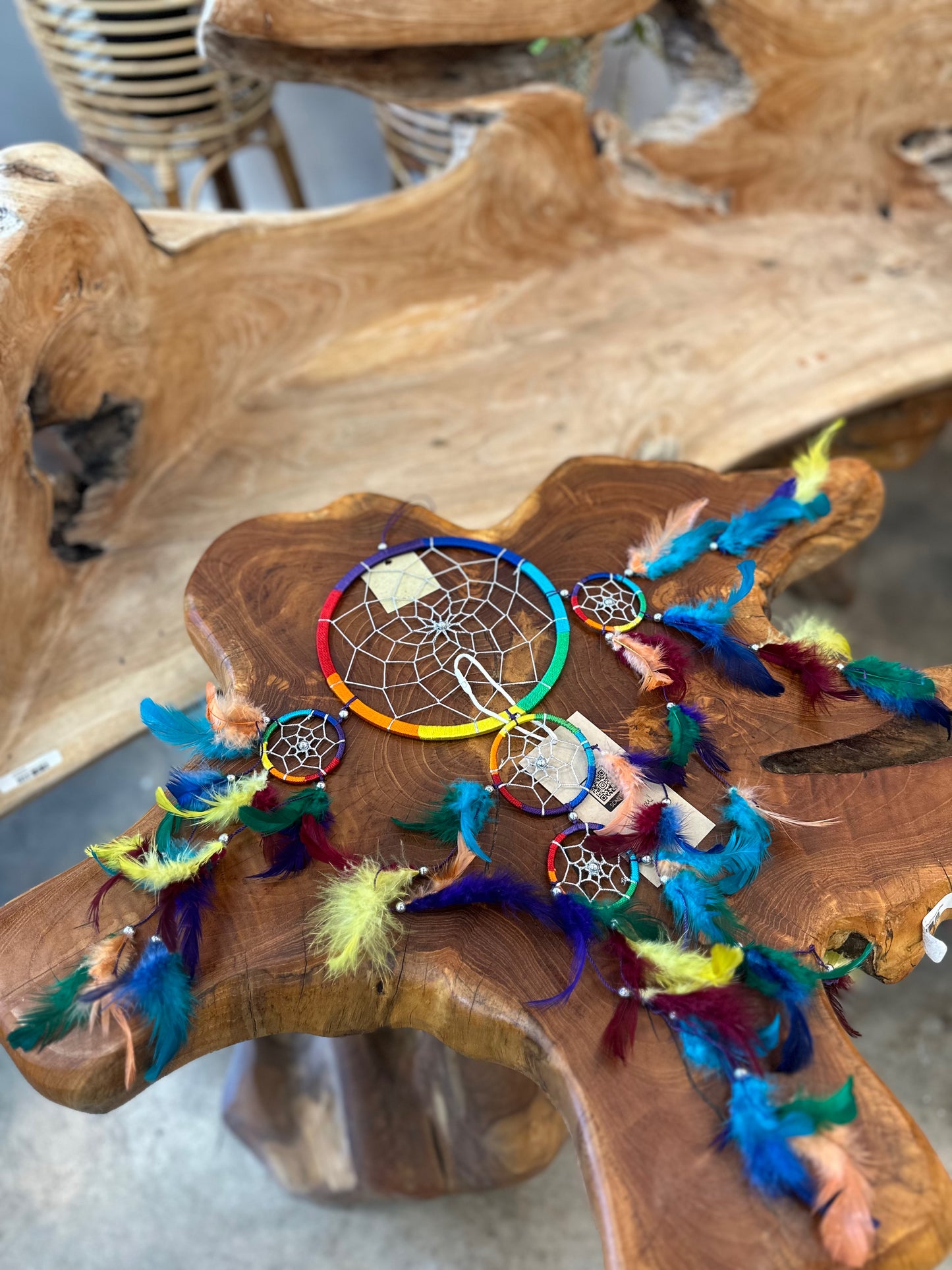 vibrant rainbow dreamcatcher with colorful feathers resting on a rustic wooden table