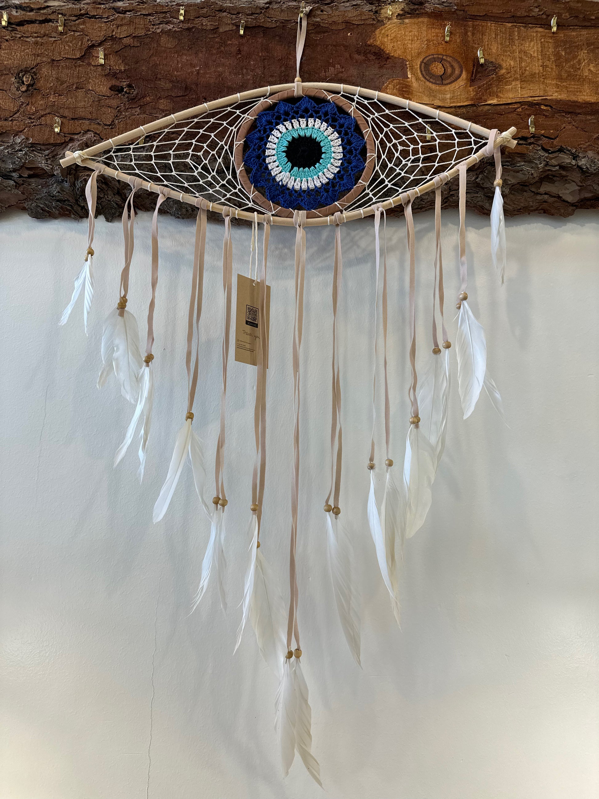 large dreamcatcher shaped like an eye with a blue iris and white feathers hanging from the bottom