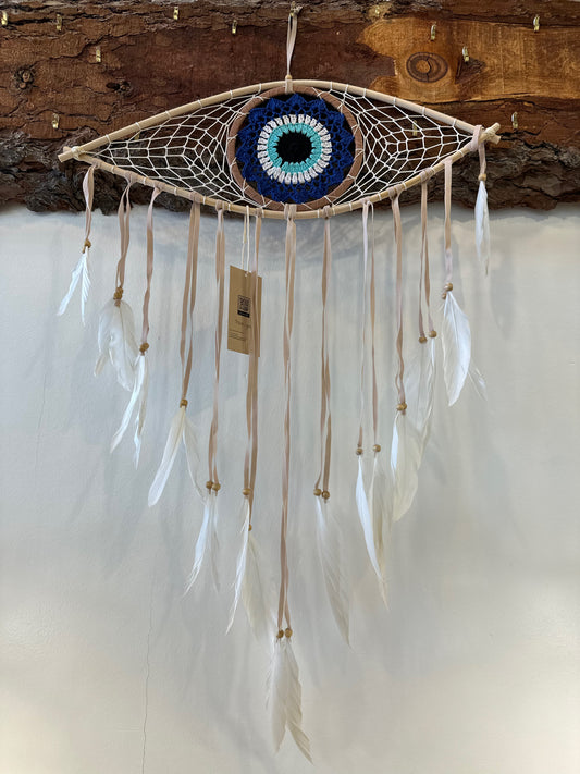 large dreamcatcher shaped like an eye with a blue iris and white feathers hanging from the bottom